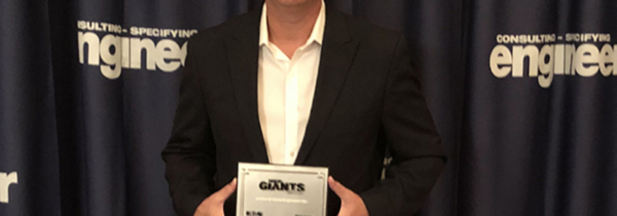 Photo of Jordan & Skala Engineers' Principal, Ross Bush, holding a plaque stating that JSE is a 2018 MEP Giant