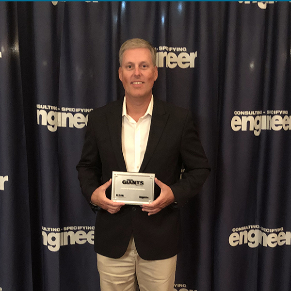 Photo of Jordan & Skala Engineers' Principal, Ross Bush, holding a plaque stating that JSE is a 2018 MEP Giant